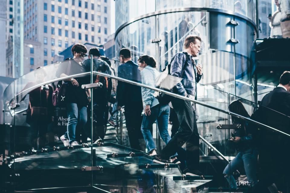 Business professionals crossing a glass walkway between offices