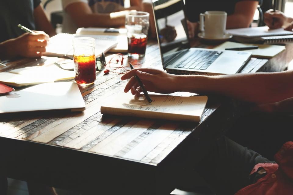 Editorial team planning content around a table with notebooks and coffee