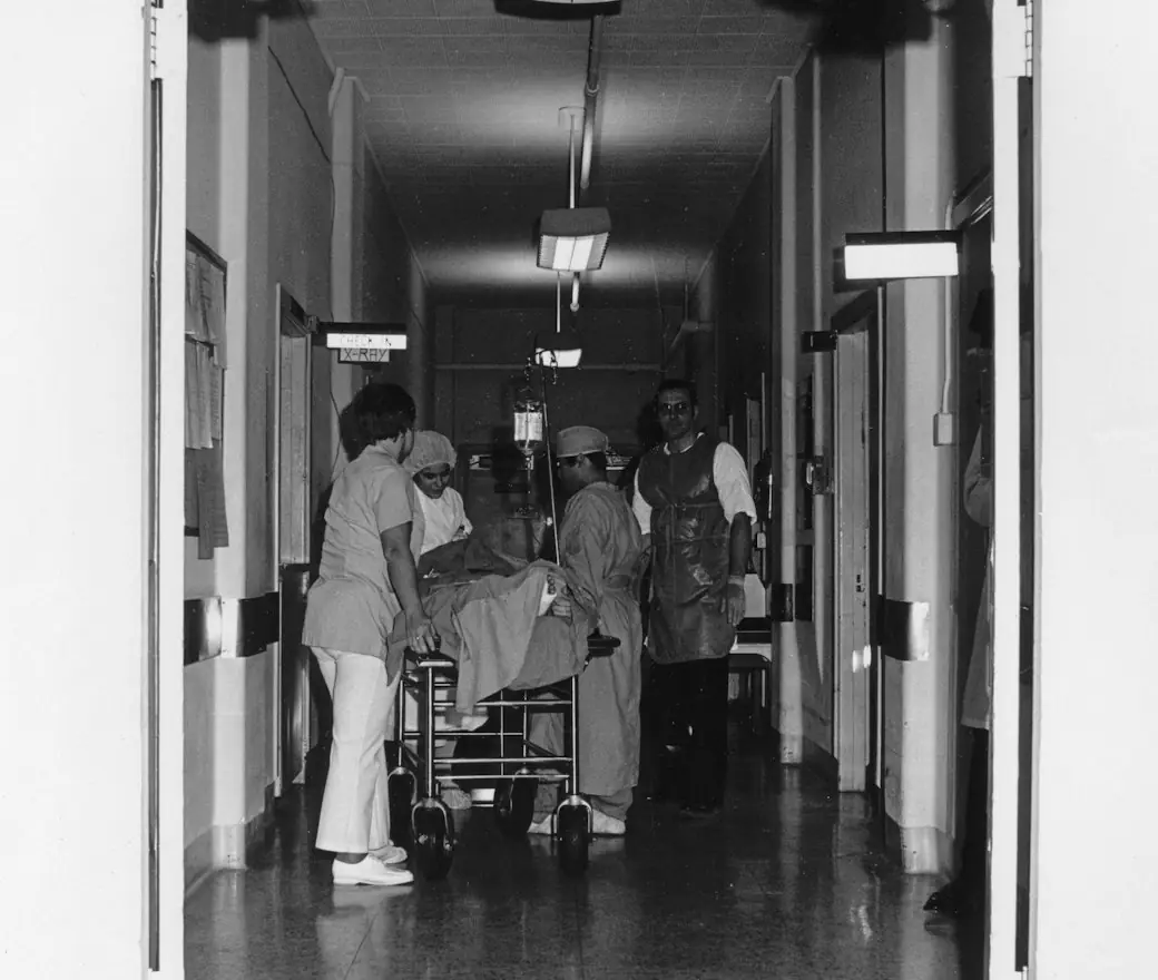 Medical staff moving a patient down a hospital hallway